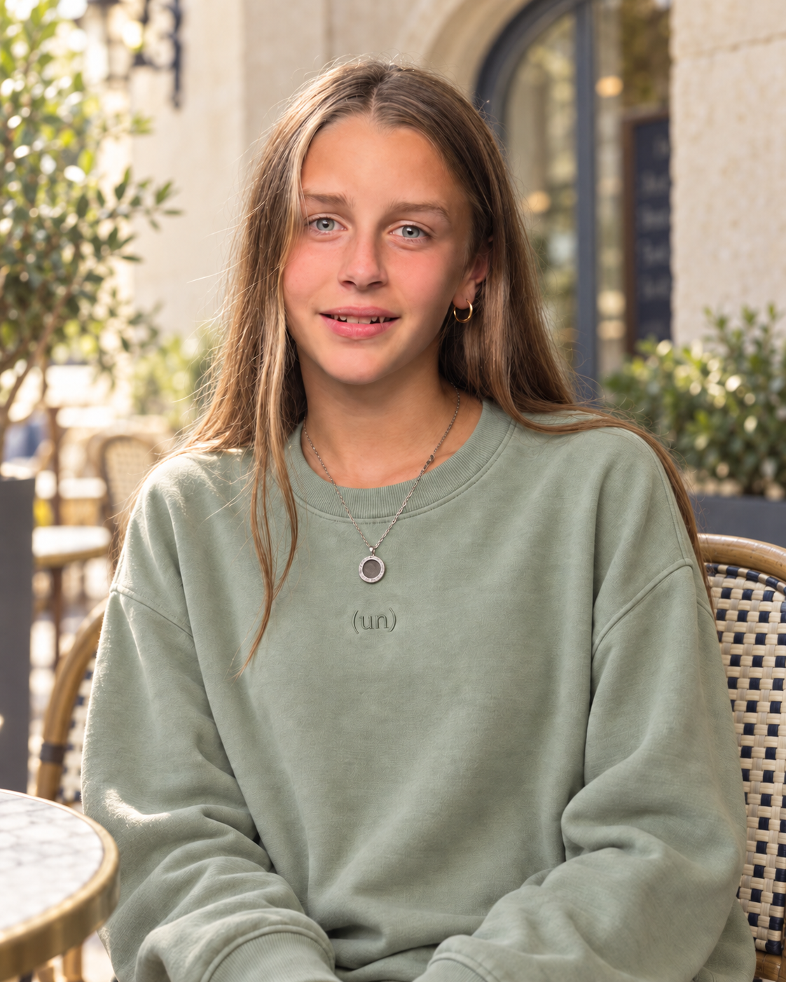 Miah Meccage at a sunlit café wearing the sage (un)comfy crew